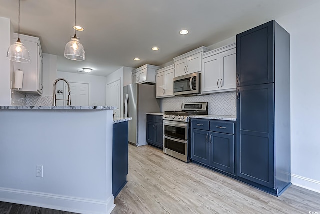 kitchen featuring light wood finished floors, backsplash, appliances with stainless steel finishes, a sink, and blue cabinets