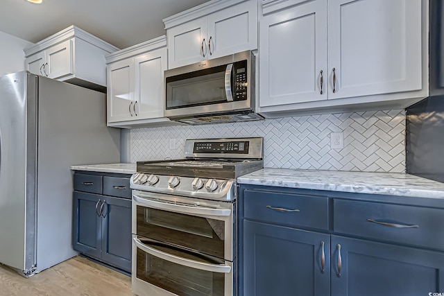 kitchen with tasteful backsplash, appliances with stainless steel finishes, light wood-style floors, light stone countertops, and blue cabinets