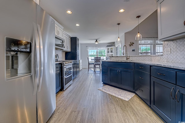 kitchen featuring a peninsula, blue cabinets, appliances with stainless steel finishes, and a sink