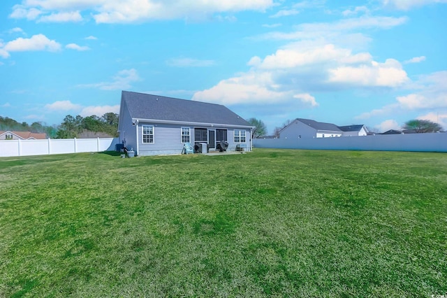 rear view of property with a fenced backyard and a lawn