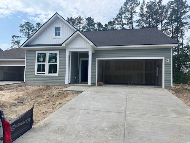 craftsman-style home with board and batten siding, central air condition unit, a garage, and concrete driveway