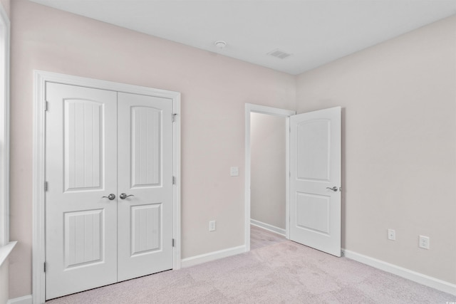 unfurnished bedroom with a closet, carpet flooring, visible vents, and baseboards