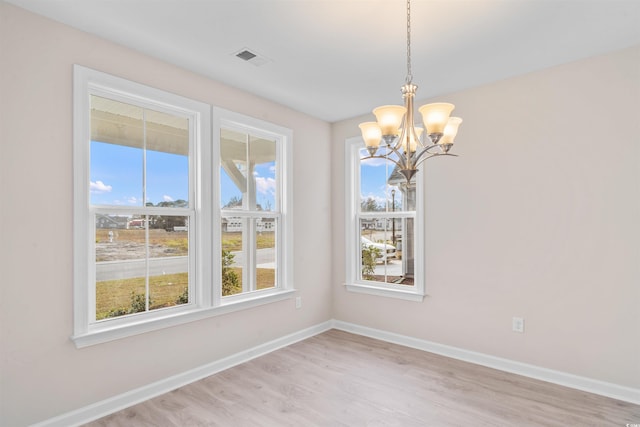 unfurnished dining area with a notable chandelier, light wood finished floors, visible vents, and baseboards