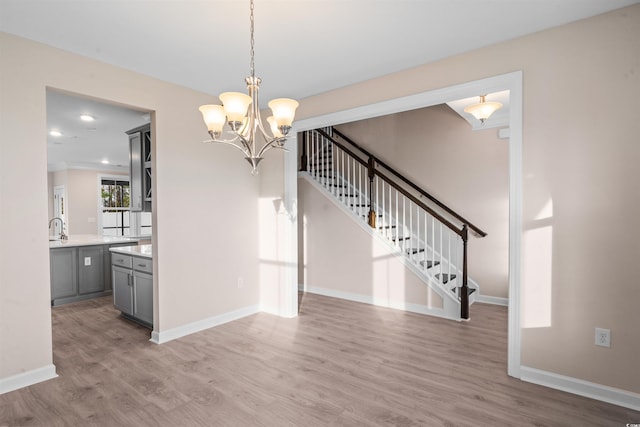 interior space featuring wood finished floors, a sink, baseboards, and stairs