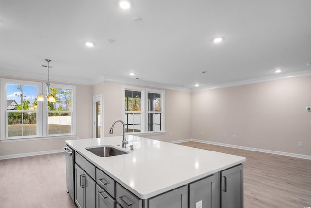 kitchen with a center island with sink, gray cabinetry, ornamental molding, a sink, and dishwasher