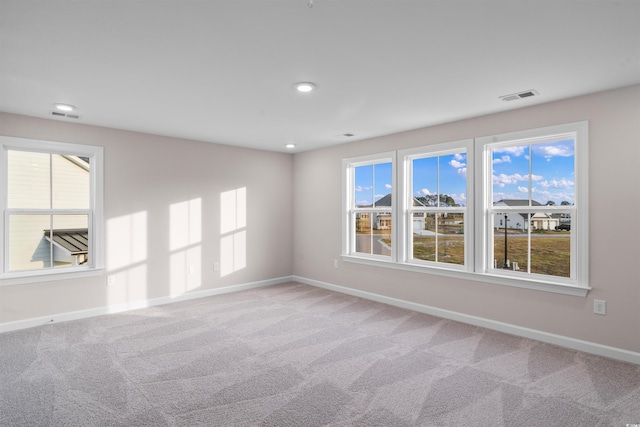 unfurnished room with carpet, visible vents, and baseboards