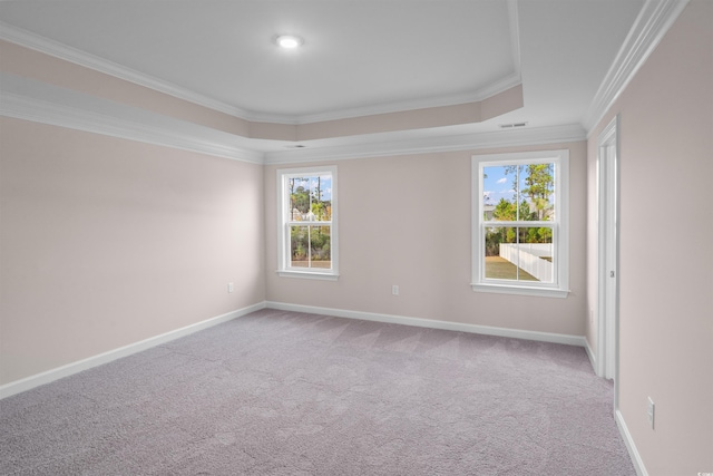 carpeted spare room featuring ornamental molding, a raised ceiling, visible vents, and baseboards