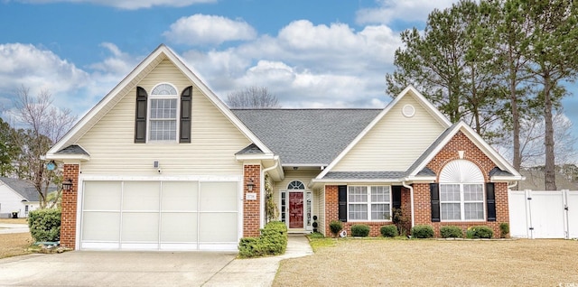 traditional home with a garage, concrete driveway, a gate, fence, and brick siding