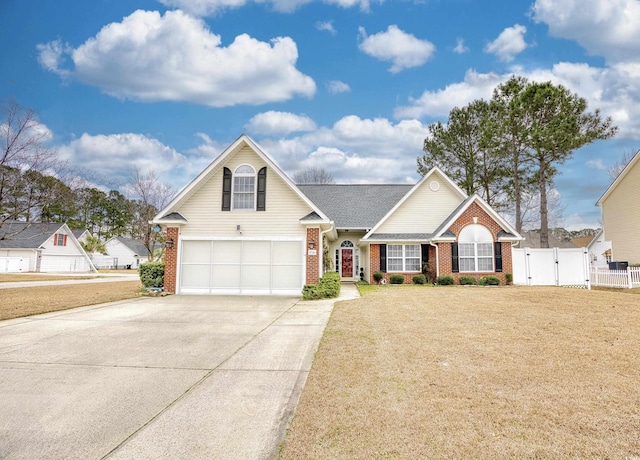 traditional-style home featuring driveway, a gate, fence, a front lawn, and brick siding