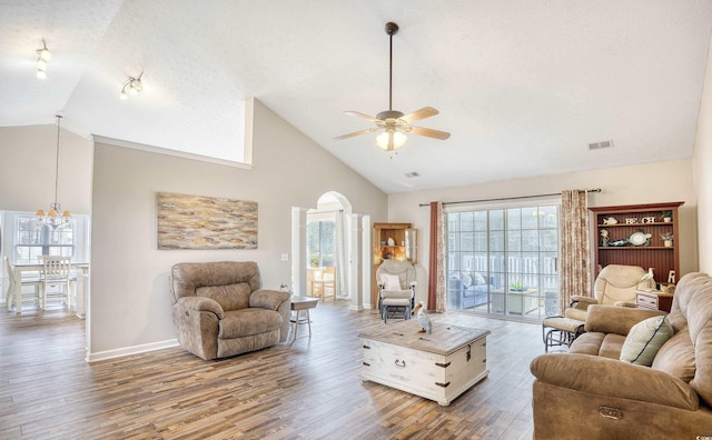 living room featuring arched walkways, a textured ceiling, wood finished floors, baseboards, and ceiling fan with notable chandelier