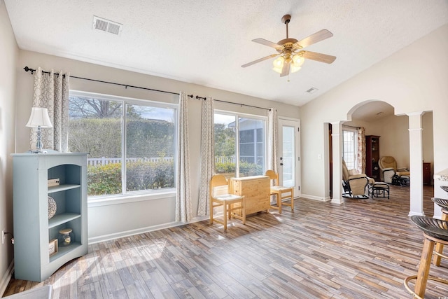 unfurnished room featuring lofted ceiling, decorative columns, visible vents, and wood finished floors