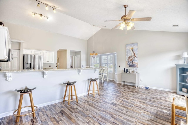 kitchen with stainless steel fridge, a breakfast bar area, and wood finished floors