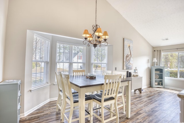 dining room featuring a textured ceiling, wood finished floors, visible vents, baseboards, and an inviting chandelier