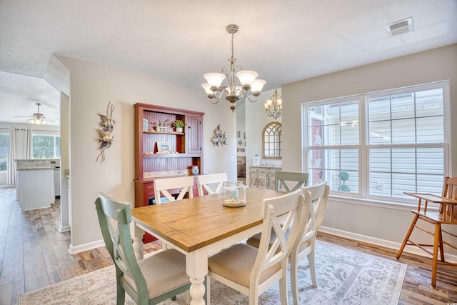 dining space featuring baseboards, a textured ceiling, visible vents, and wood finished floors