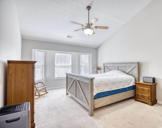 bedroom featuring lofted ceiling, a textured ceiling, visible vents, and light colored carpet