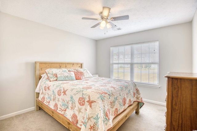 carpeted bedroom featuring a textured ceiling, ceiling fan, visible vents, and baseboards