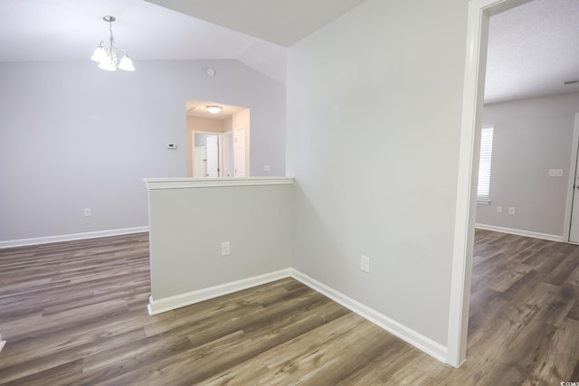 empty room with vaulted ceiling, dark wood-style flooring, and baseboards