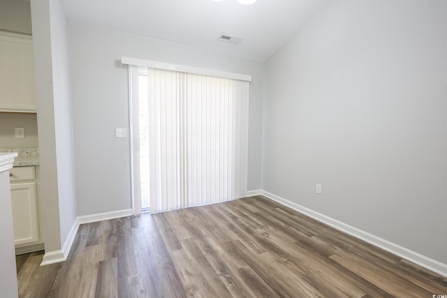 spare room featuring wood finished floors, visible vents, and baseboards