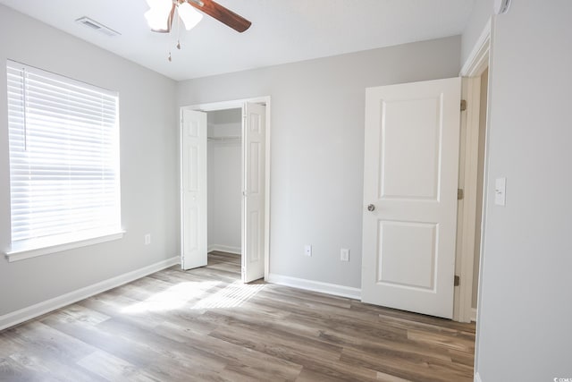 unfurnished bedroom with baseboards, a closet, visible vents, and wood finished floors