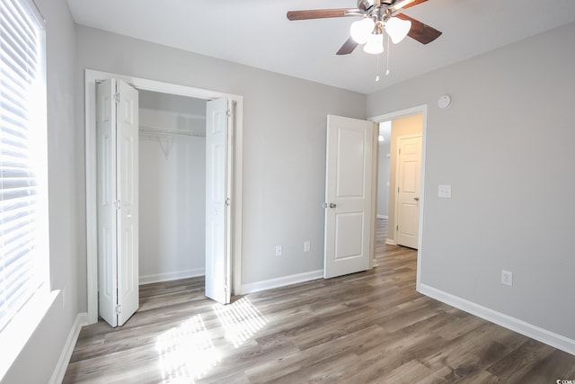 unfurnished bedroom featuring multiple windows, wood finished floors, and baseboards