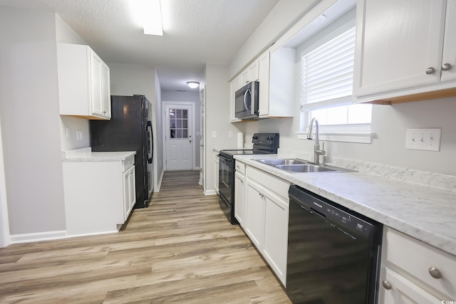 kitchen featuring black appliances, white cabinets, a sink, and light countertops