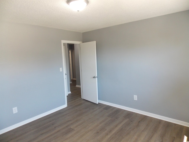 unfurnished room featuring dark wood-style floors, a textured ceiling, and baseboards