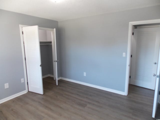 unfurnished bedroom featuring a closet, wood finished floors, and baseboards