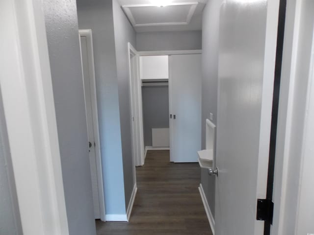 hallway featuring attic access, dark wood finished floors, and baseboards