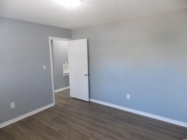 spare room featuring a textured ceiling, baseboards, and wood finished floors