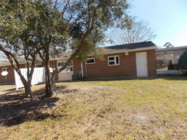 back of house featuring fence, central AC unit, a lawn, and brick siding