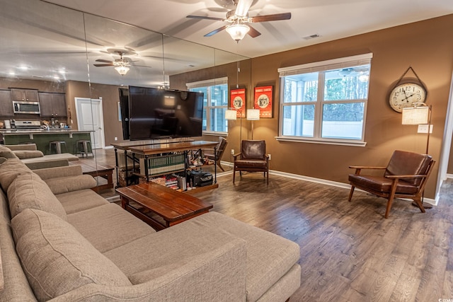 living area featuring baseboards, ceiling fan, visible vents, and wood finished floors