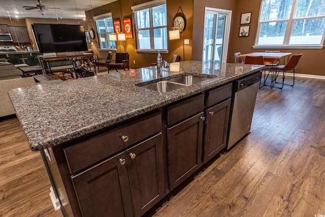 kitchen with a center island with sink, open floor plan, dark wood-style flooring, stainless steel dishwasher, and a sink