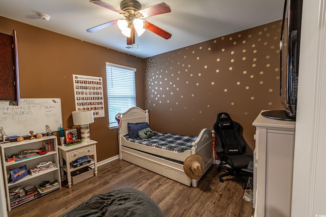 bedroom with a ceiling fan, visible vents, baseboards, and wood finished floors