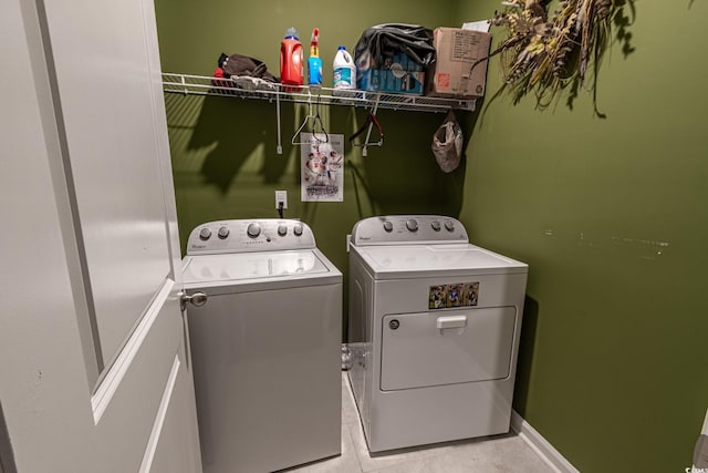 clothes washing area featuring baseboards, laundry area, light tile patterned floors, and washer and dryer