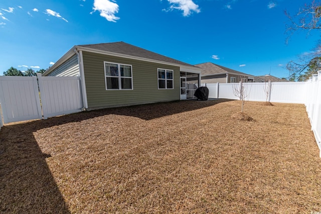 rear view of property with a fenced backyard and a yard