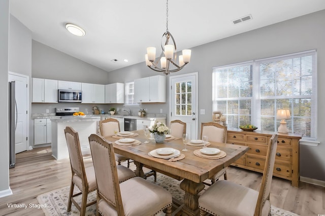 dining area with light wood finished floors, visible vents, a healthy amount of sunlight, and a notable chandelier