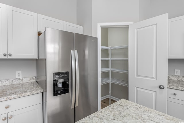 kitchen featuring white cabinets, light stone countertops, and stainless steel fridge