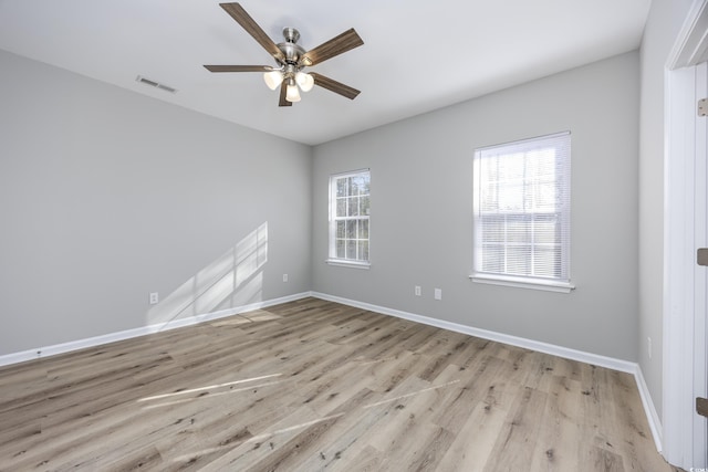 spare room featuring wood finished floors, baseboards, visible vents, and ceiling fan