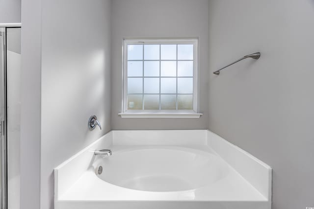 full bathroom featuring a wealth of natural light, a bath, and a shower with door