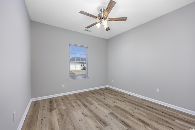 empty room featuring wood finished floors, visible vents, baseboards, and ceiling fan