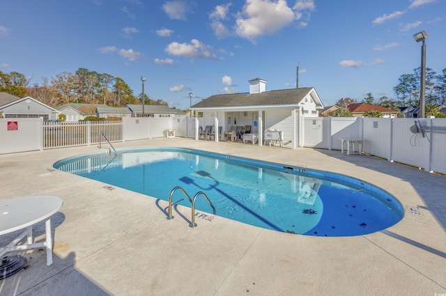 community pool with a patio area and fence