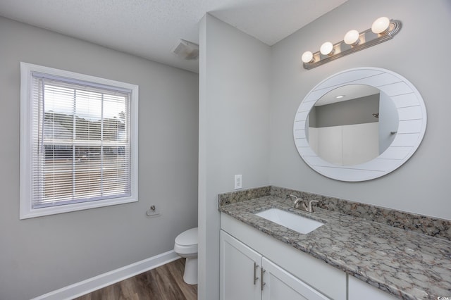 bathroom featuring toilet, a textured ceiling, wood finished floors, baseboards, and vanity