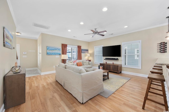 living room featuring light wood-type flooring, visible vents, and crown molding