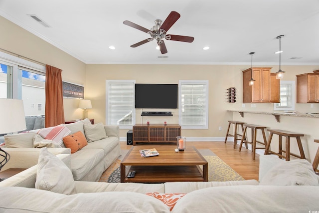 living room with recessed lighting, visible vents, baseboards, light wood-type flooring, and crown molding