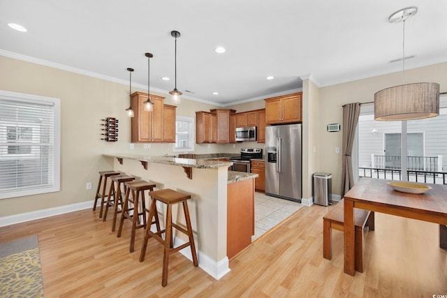 kitchen with ornamental molding, a kitchen breakfast bar, a peninsula, light stone countertops, and stainless steel appliances