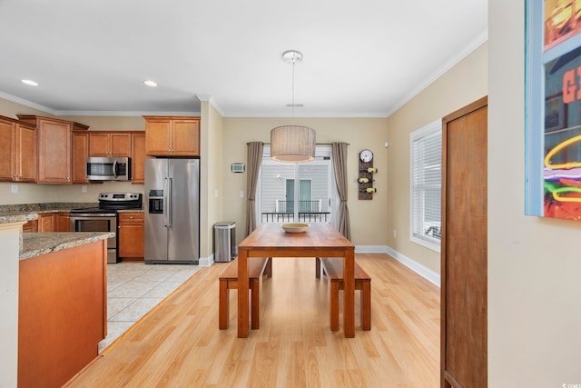 dining room featuring baseboards, light wood-type flooring, and crown molding