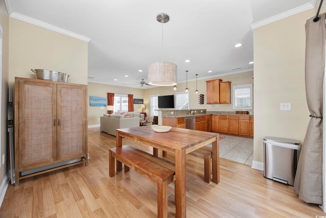 dining space with light wood-style floors, plenty of natural light, and ornamental molding