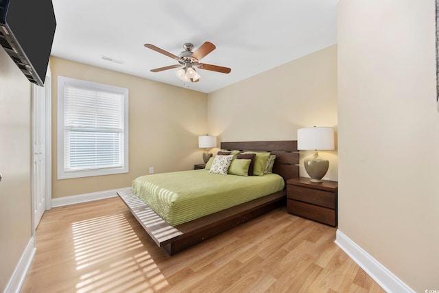 bedroom featuring a ceiling fan, visible vents, light wood-style flooring, and baseboards