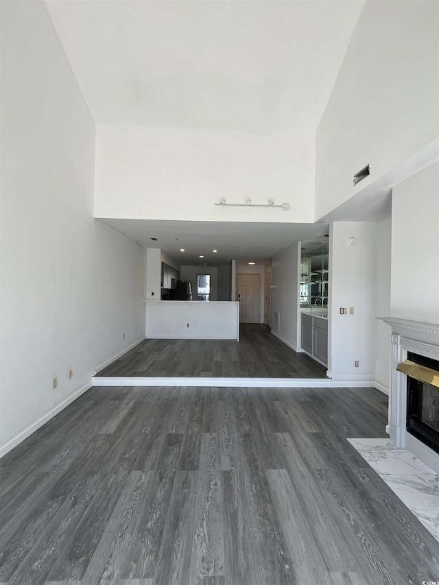 4396 Baldwin Ave Unit 141, Little River, SC 29566 - unfurnished living room featuring wood finished floors, a fireplace with flush hearth, baseboards, and a high ceiling