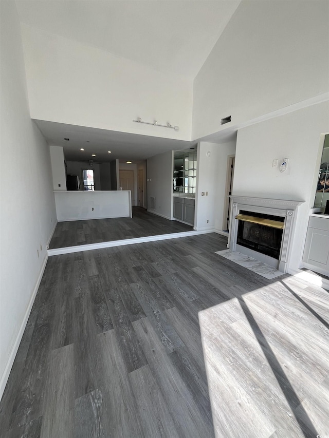 4396 Baldwin Ave Unit 141, Little River, SC 29566 - unfurnished living room with a fireplace with flush hearth, high vaulted ceiling, wood finished floors, and baseboards